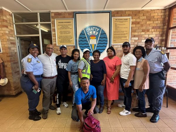 A group of individuals, including police officers and school staff, standing together in front of Chatty Senior Secondary School. They are participating in an awareness campaign about drug and alcohol abuse.